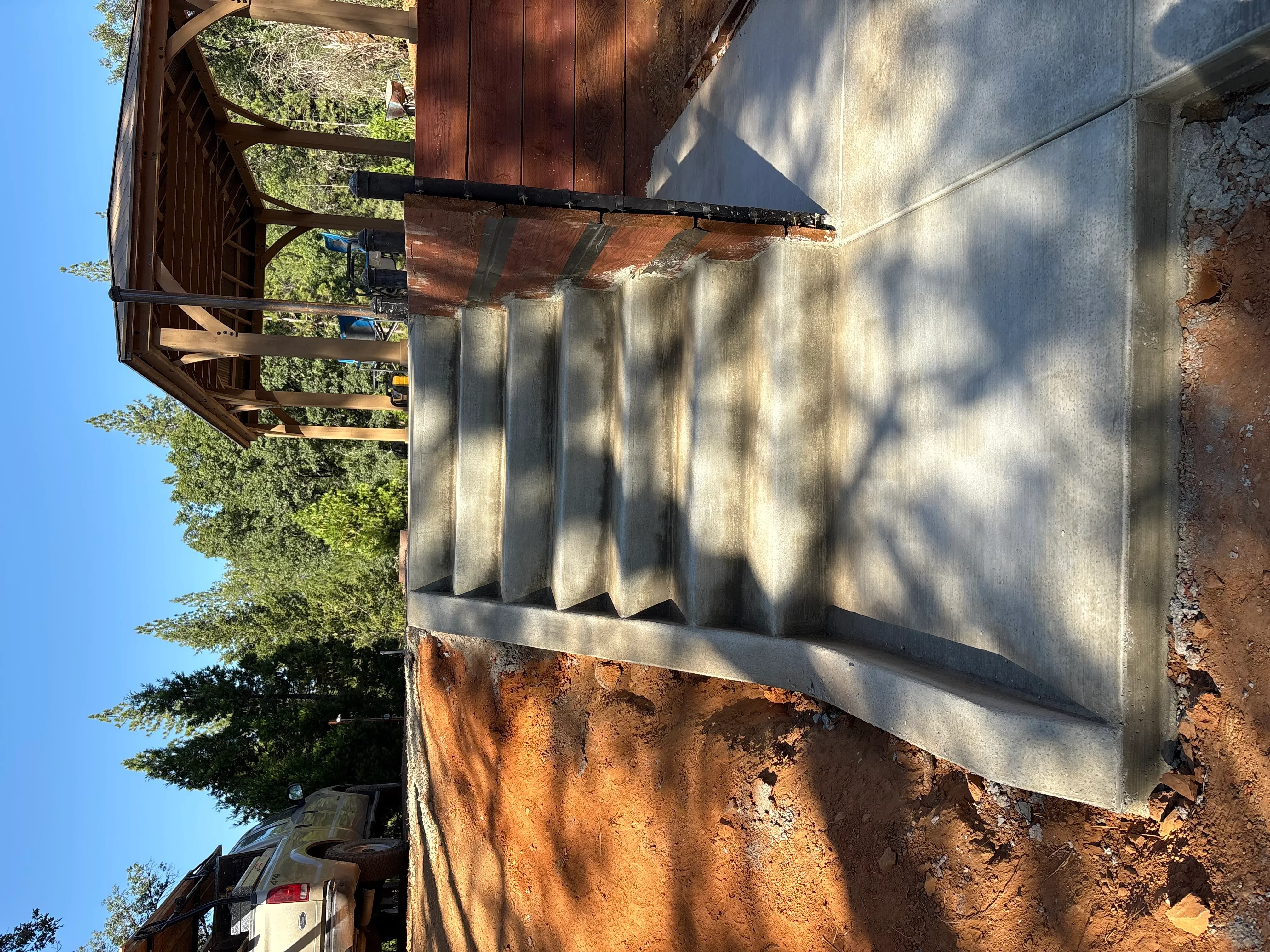 Stained wood pergola with horizontal slats over concrete pad foundation