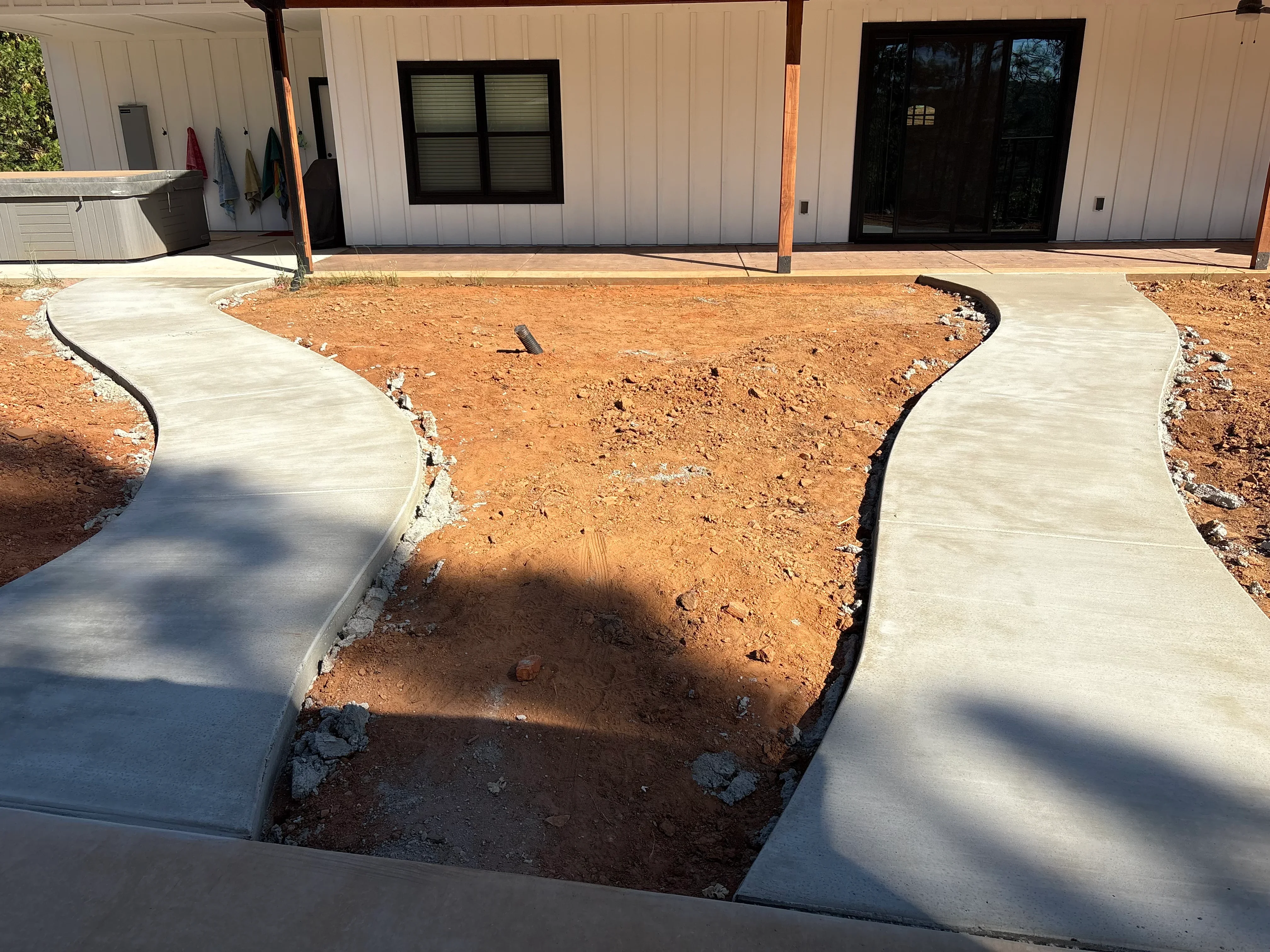 Curved concrete walkway with black metal edging around prepared soil area