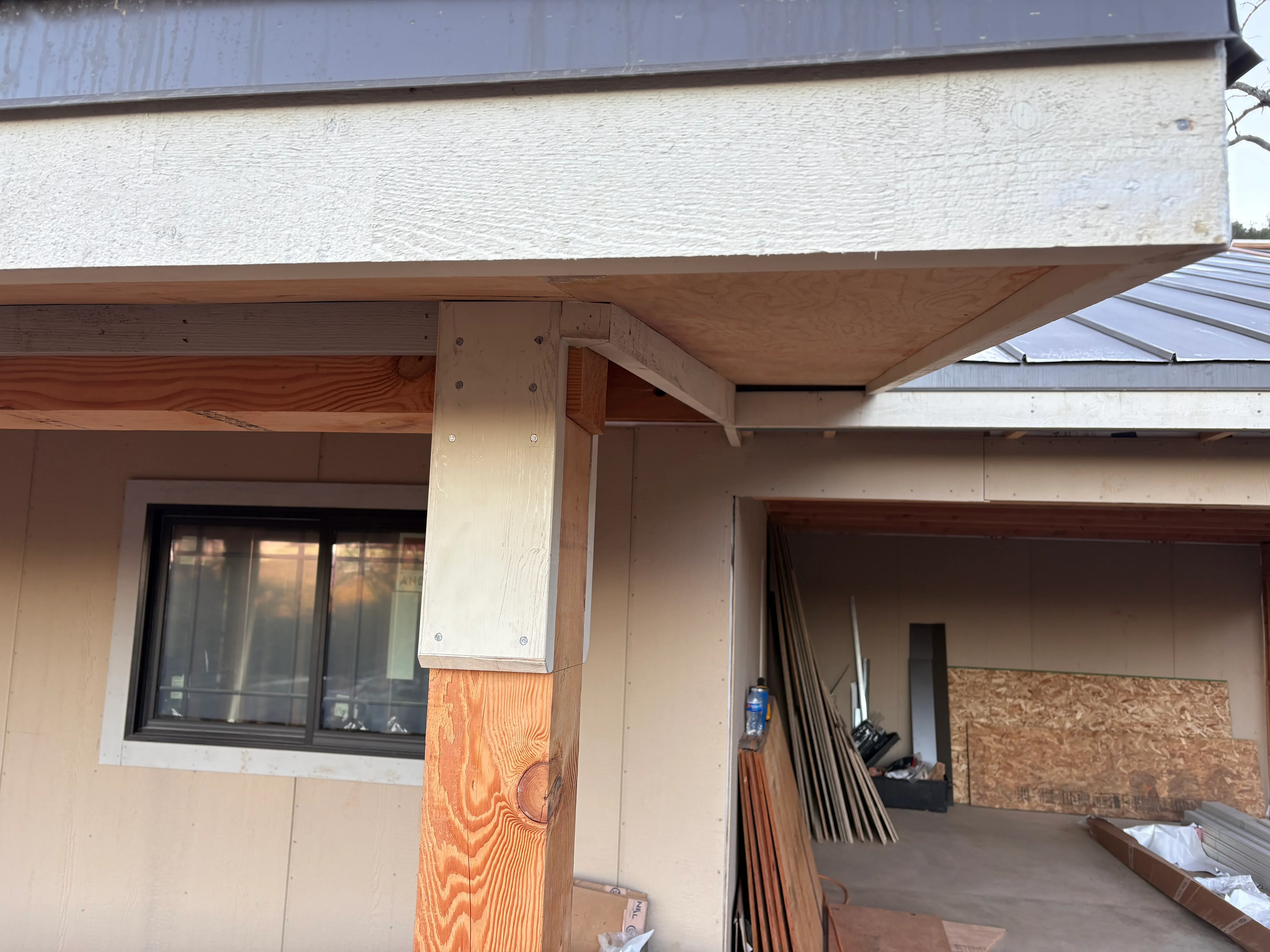 Wood beam framing, plywood soffit, and metal roof on residential addition with covered porch