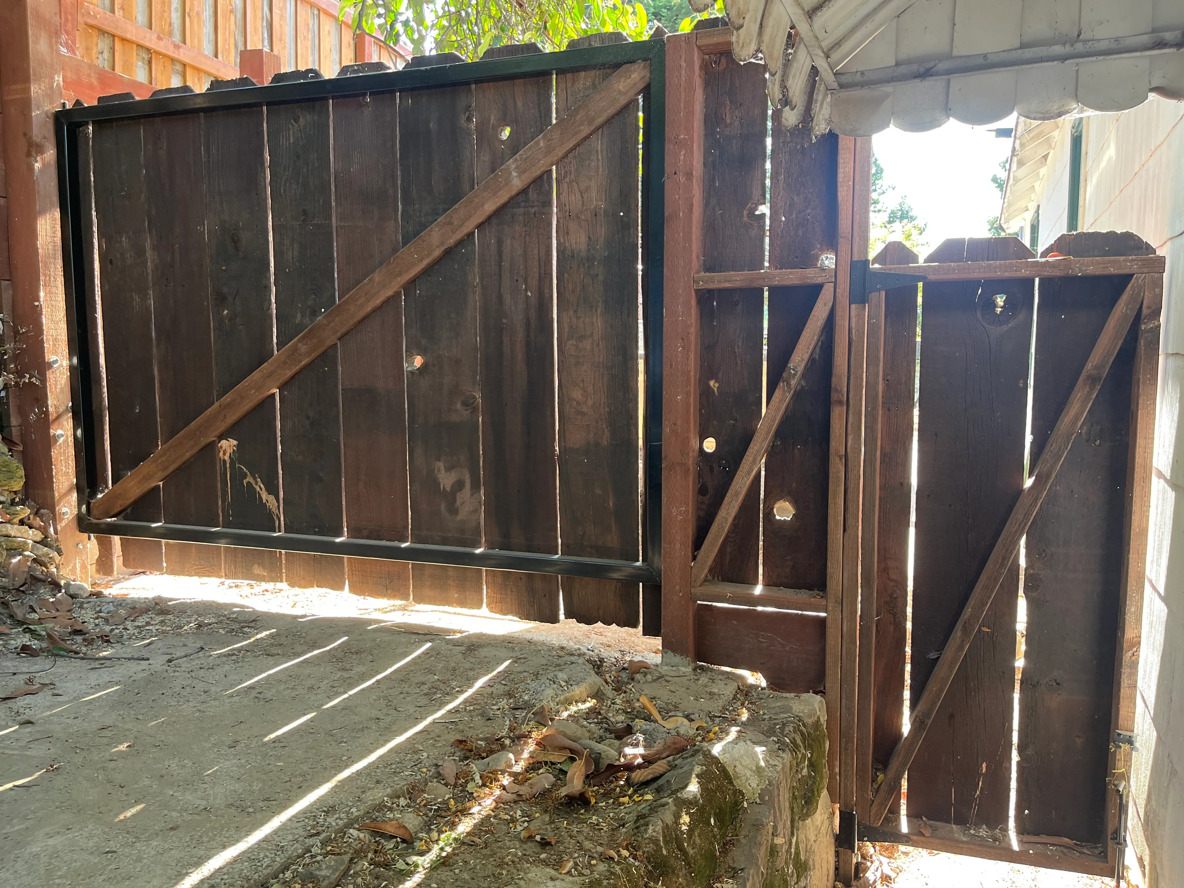 Dark-stained wood gate with diagonal bracing and metal frame, residential fence installation