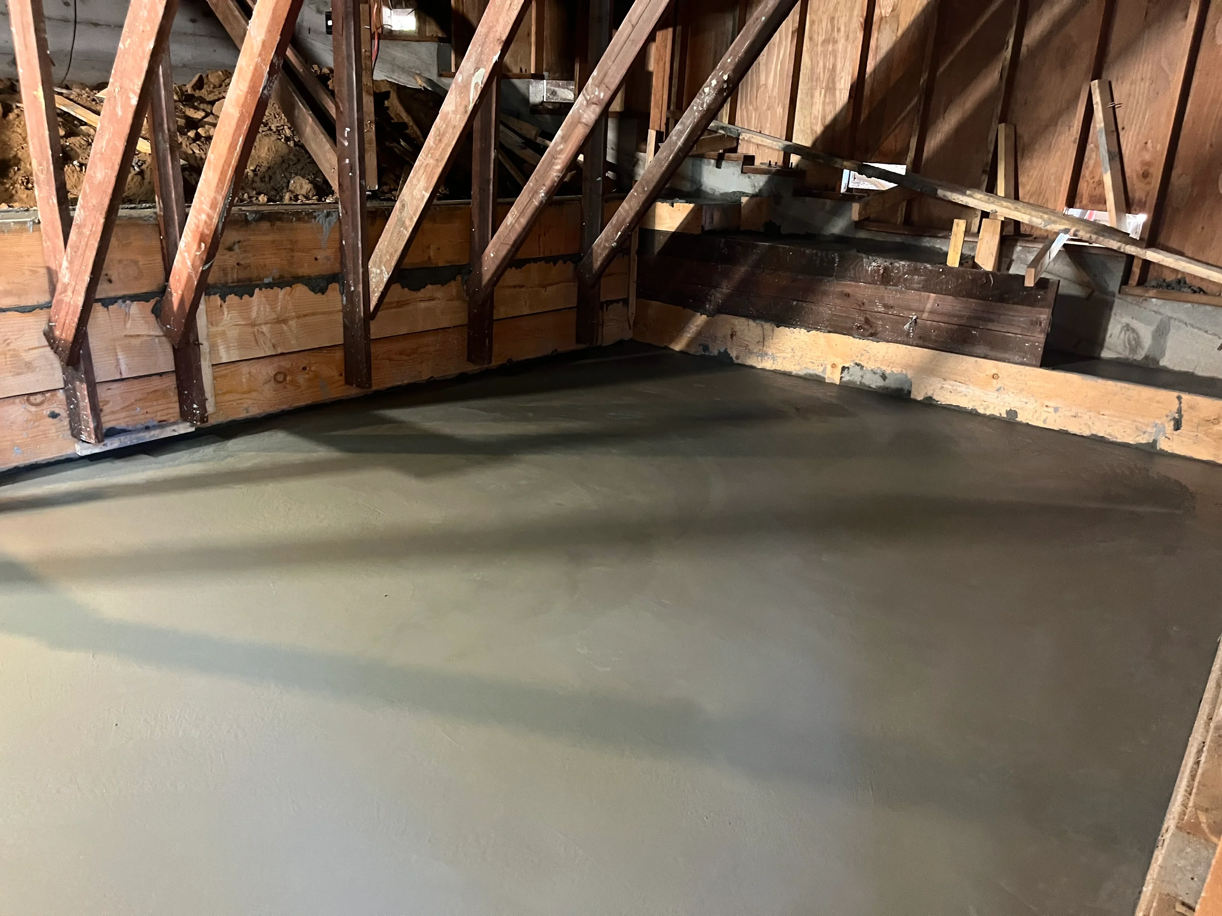 Freshly poured concrete foundation with wooden roof trusses and temporary forms