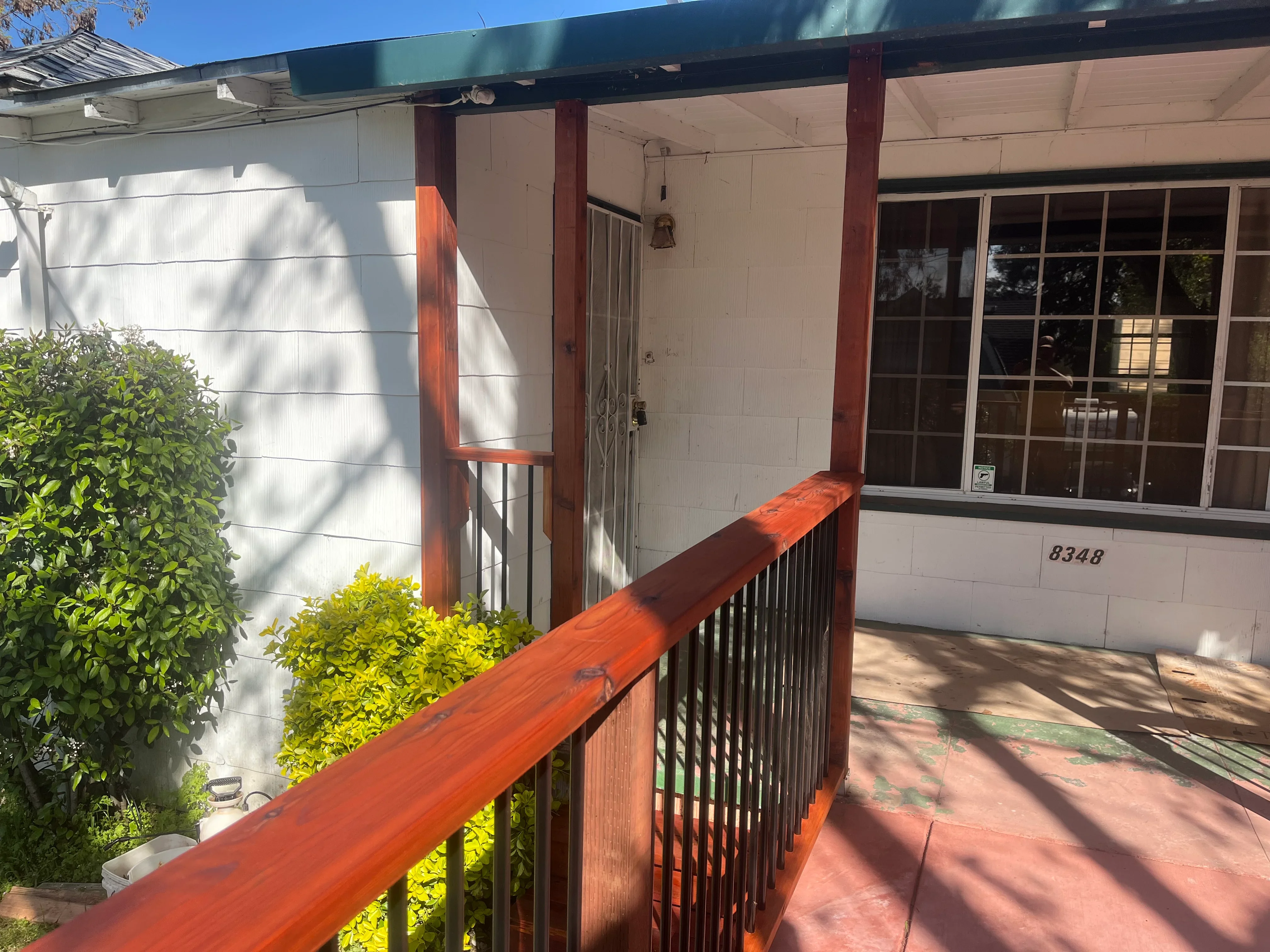 Red-stained wood porch railing and beam with vertical spindles, covered entry structure