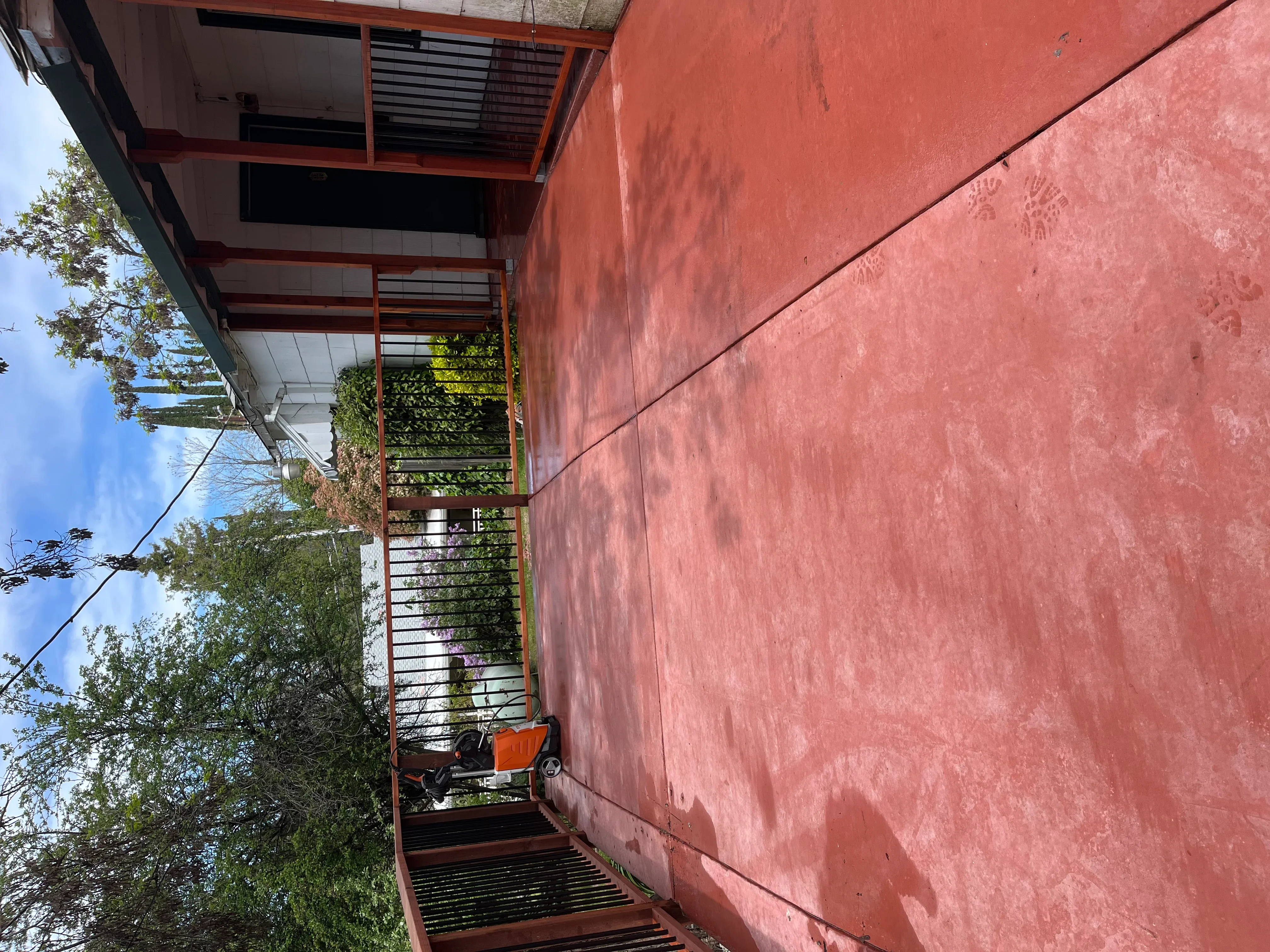 Metal staircase with cable railing, wooden treads, and covered landing at residential entrance
