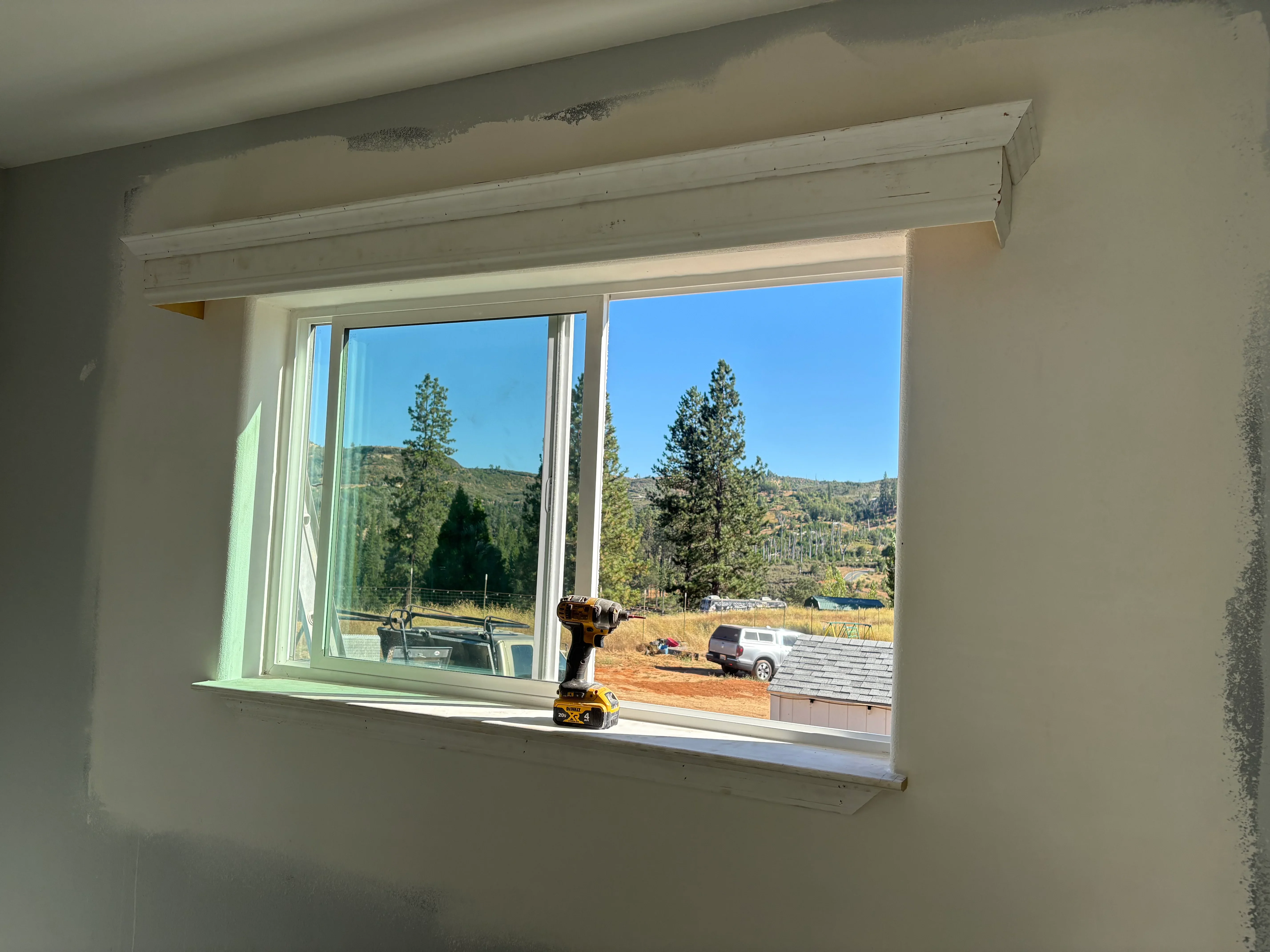 Large picture window with white trim and header beam installed in drywall opening