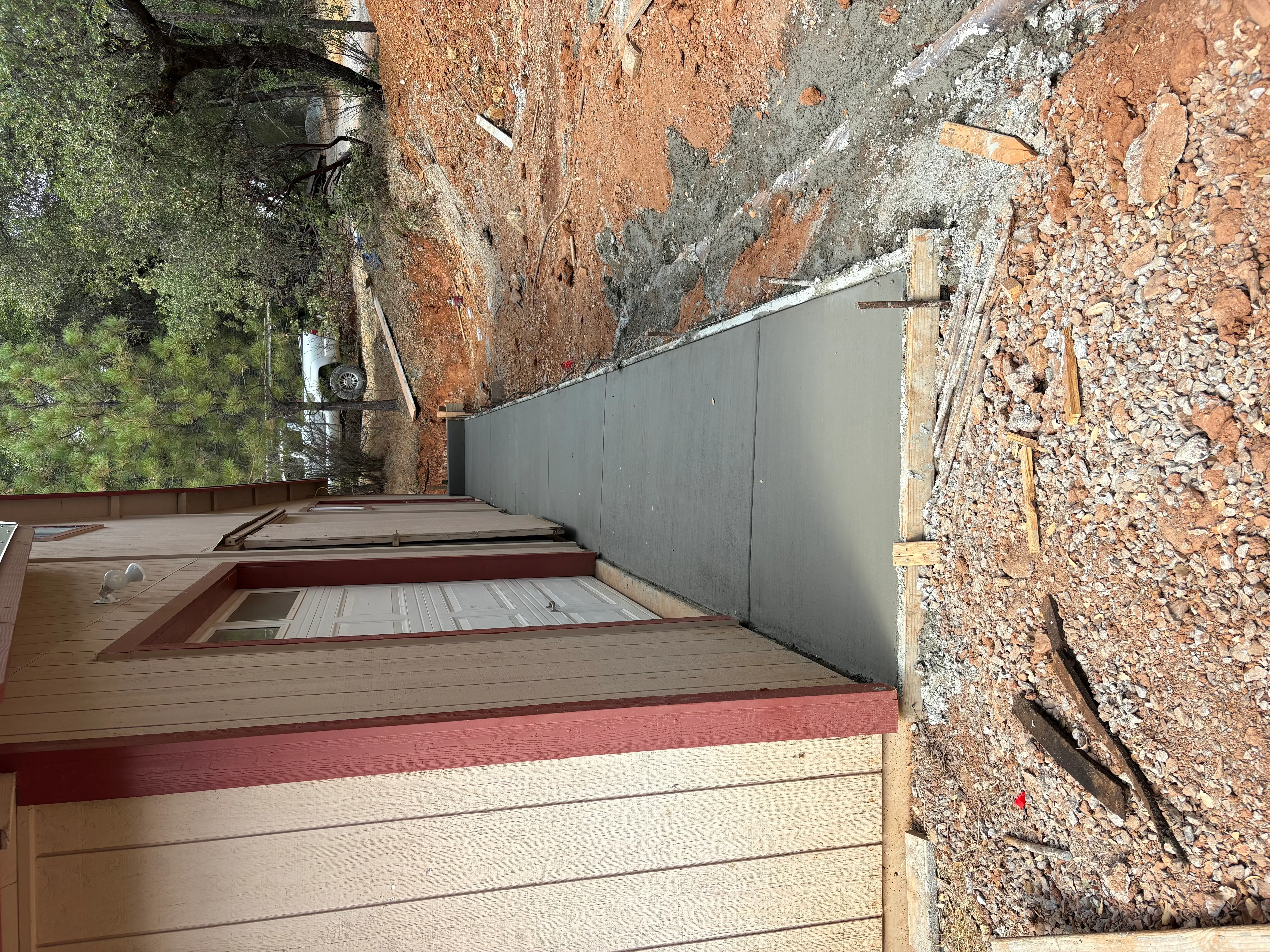 Composite deck with burgundy and tan boards, metal retaining wall, and stone foundation