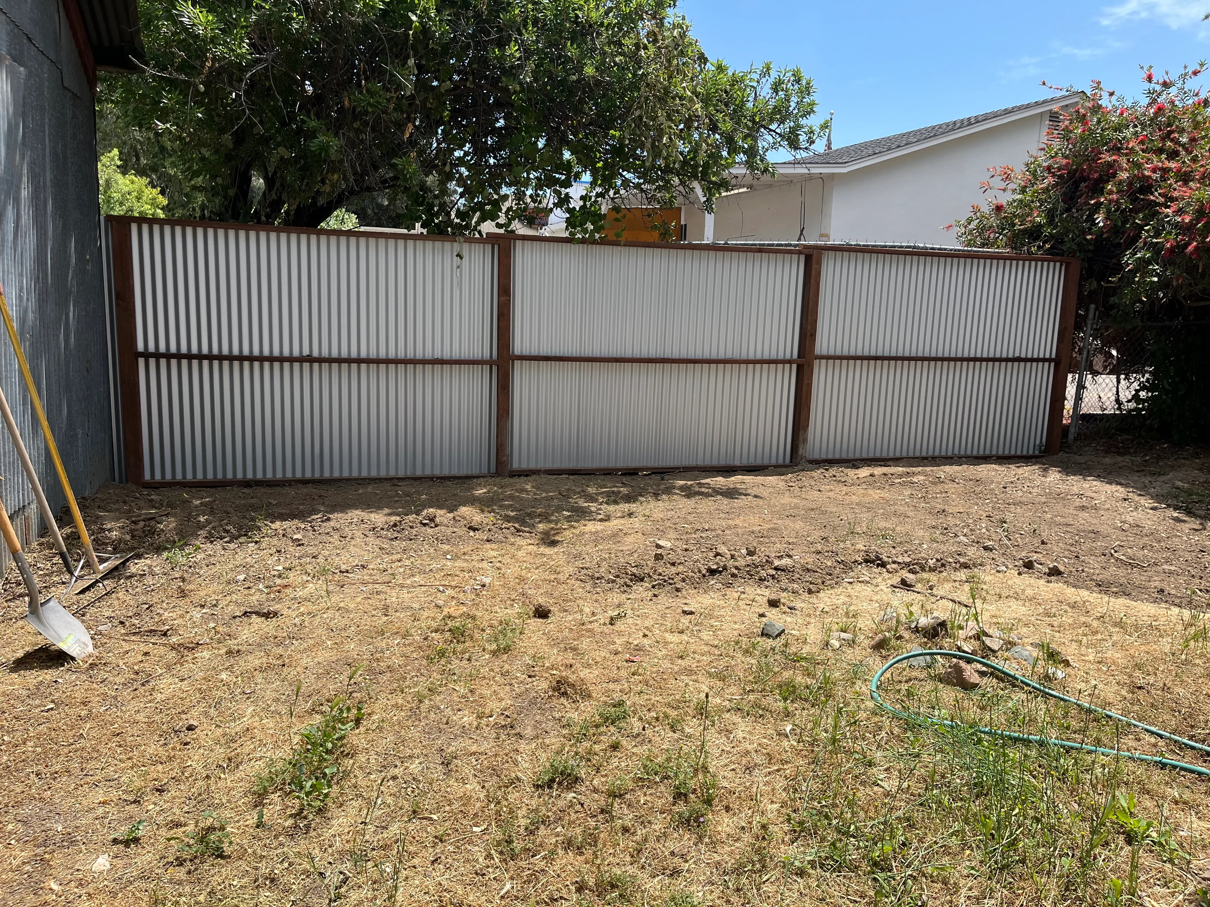 Three-panel corrugated metal fence with steel frame in residential backyard