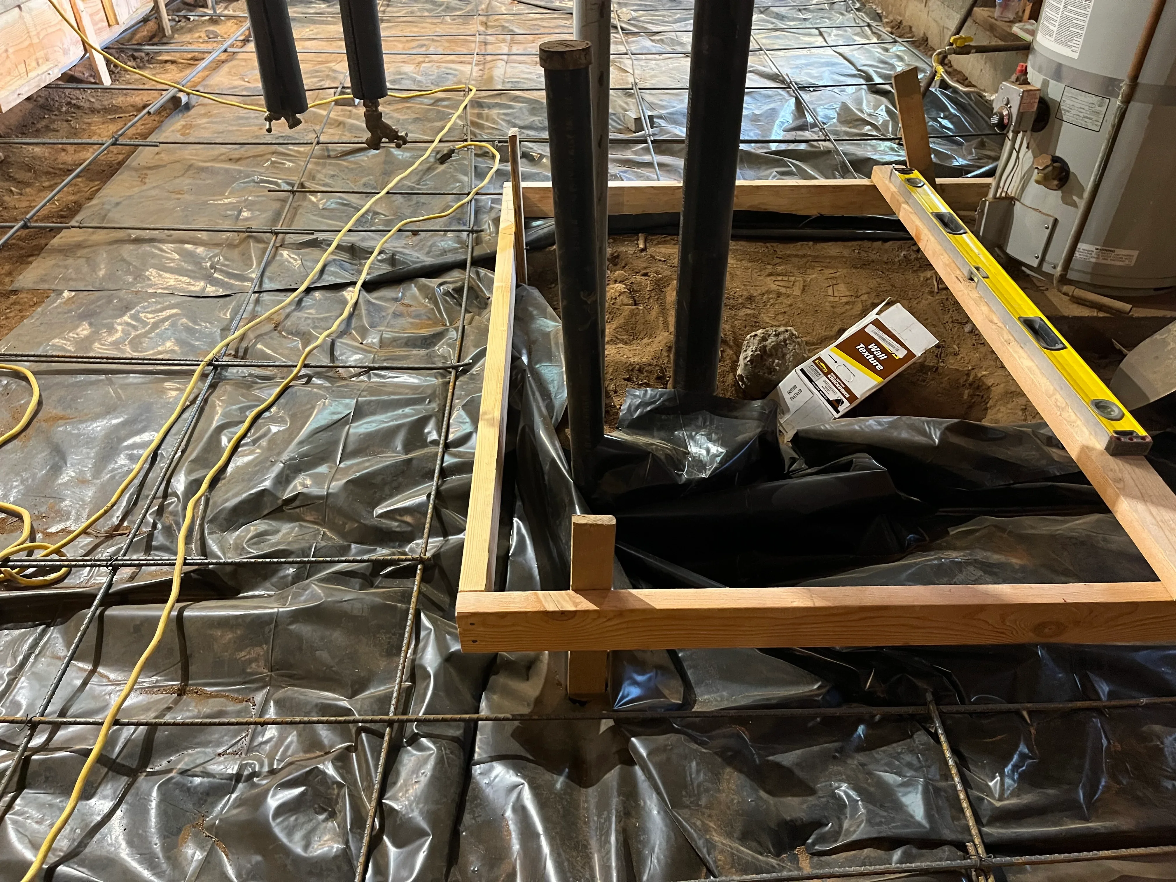 Basement framing with treated lumber joists, black vapor barrier, and electrical conduit installation