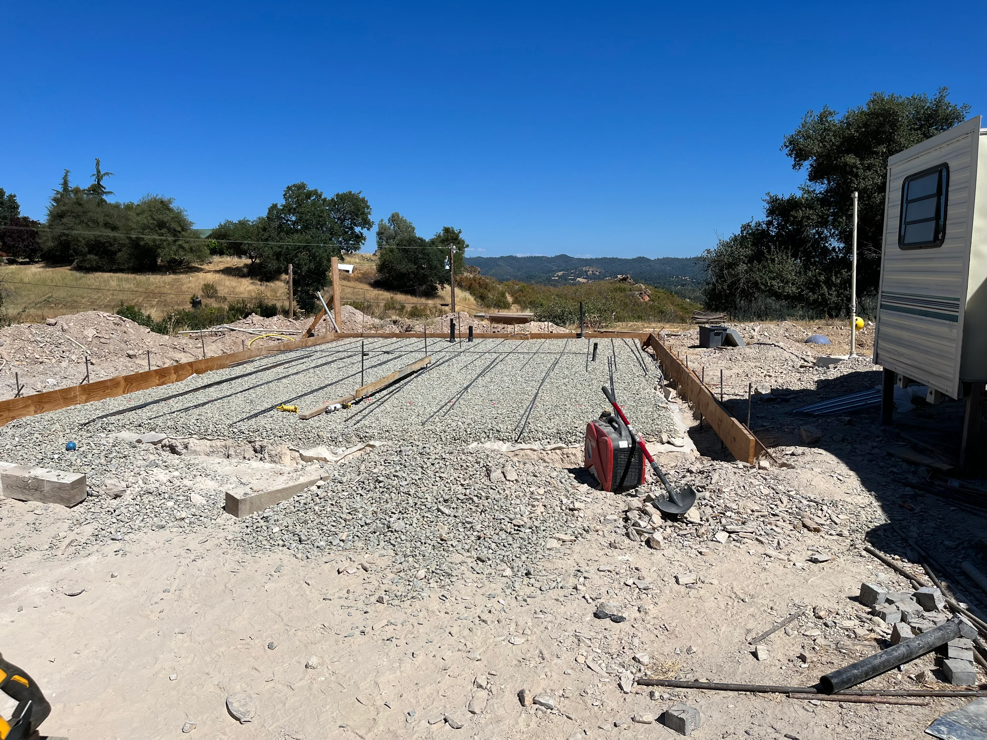Foundation with rebar grid, gravel base, wooden framing, and concrete footings on hillside