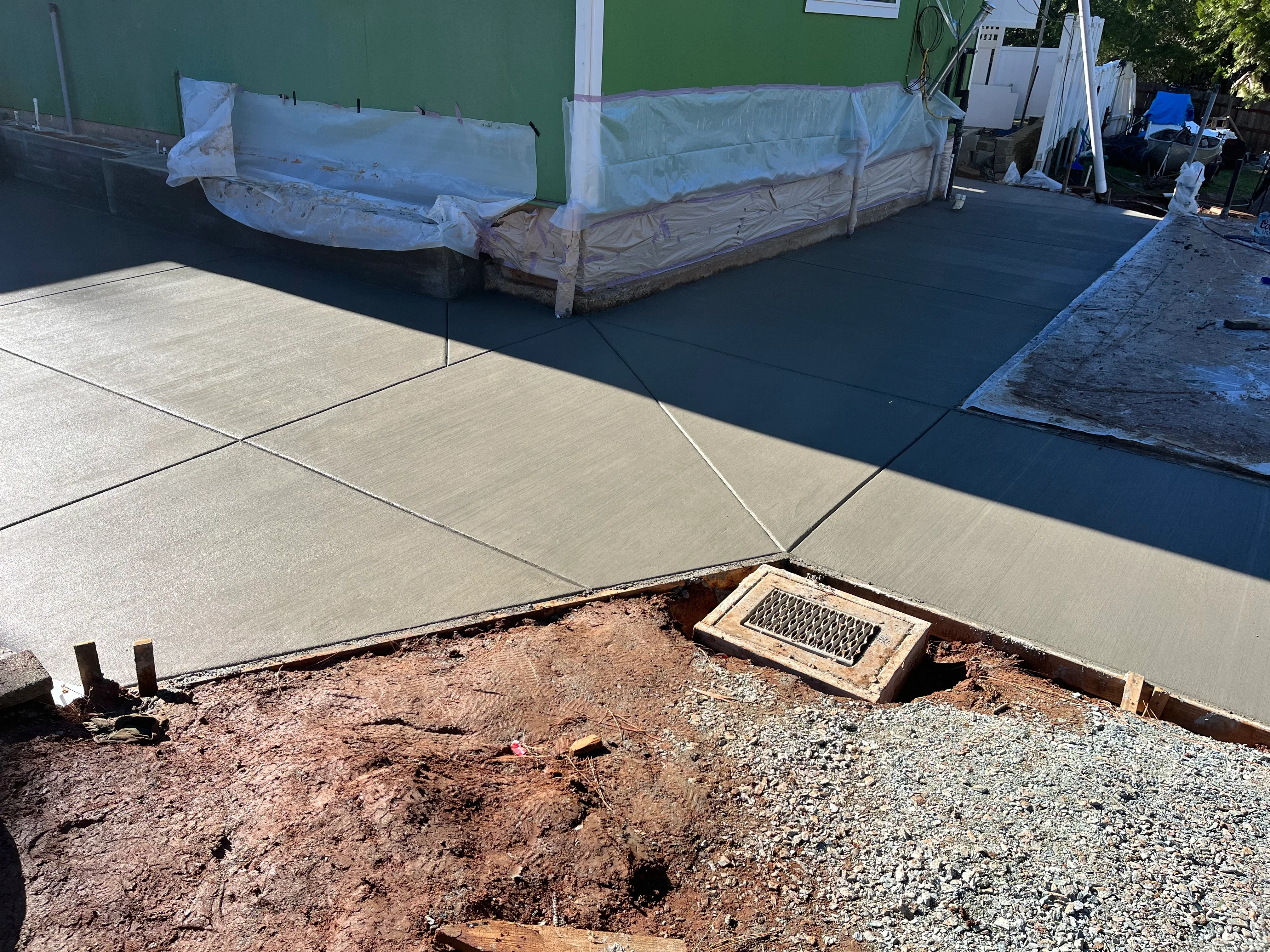 Newly poured concrete patio with control joints and metal edging during installation
