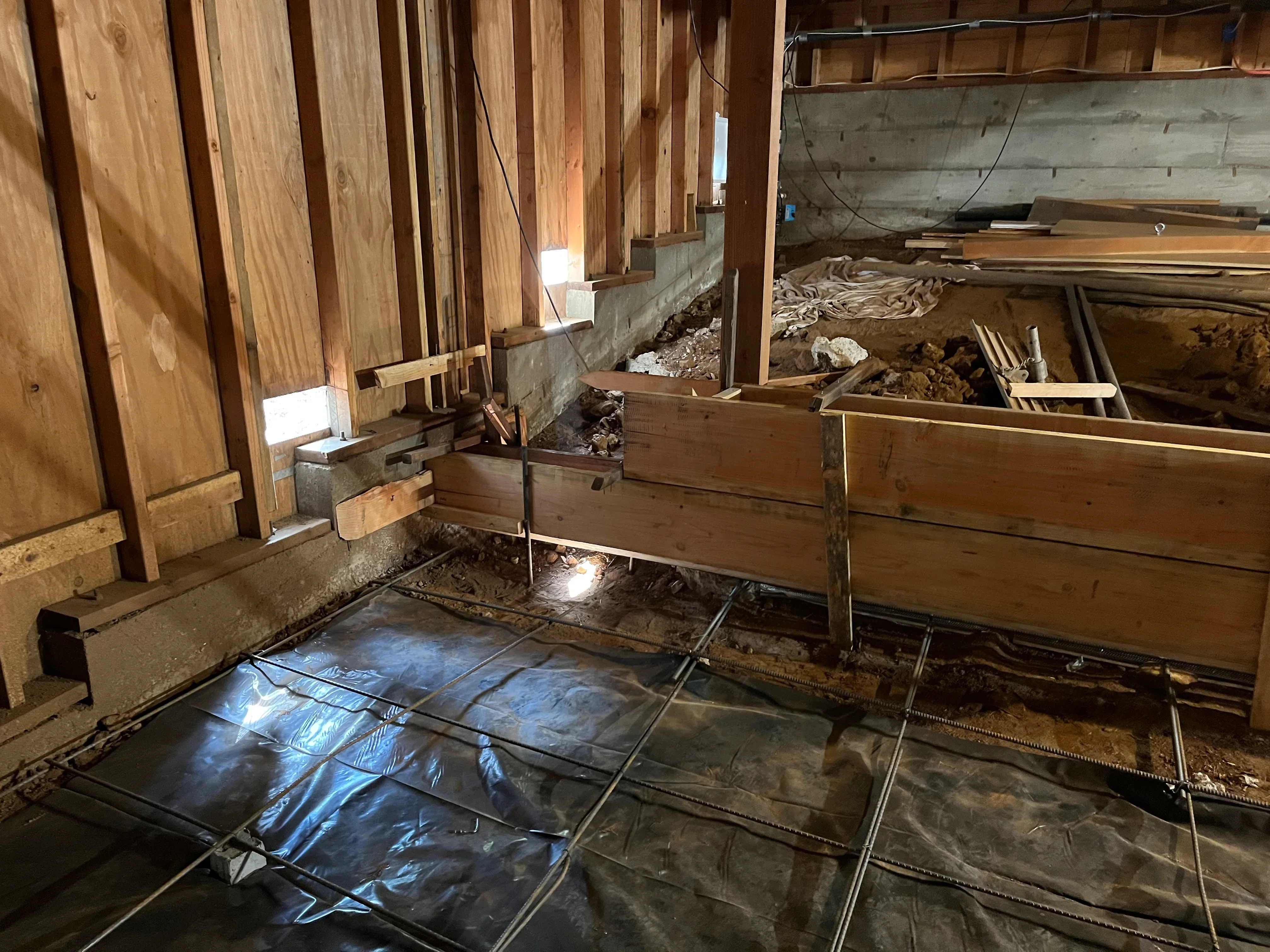 Wood framing studs, concrete foundation, and vapor barrier in residential construction